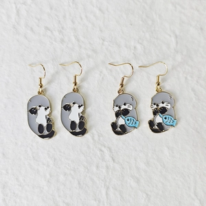 Detail of alloy sea otter earrings with blue fish enamel drops and gold hooks