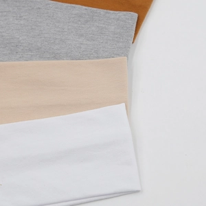 Détail de la texture en maille de bandeaux élastiques en coton blanc, beige, gris et caramel