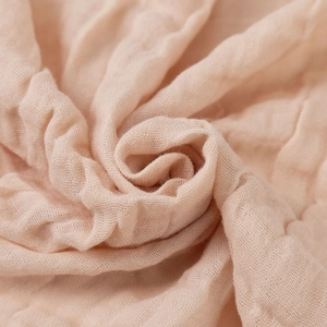 Detailed macro view of soft peach bamboo cotton gauze fabric texture and weaving