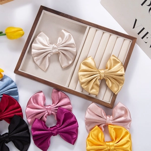 Macro view of multi-color oversized satin bow hair clips on elegant velvet jewelry tray