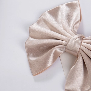 Detail of champagne satin bow hair clip showing smooth texture and fine stitching