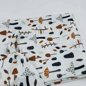 Detail of newborn swaddle set featuring earth-toned mushroom prints on soft fabric