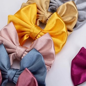Detailed close-up of large satin hair bows in various metallic colors and silk texture