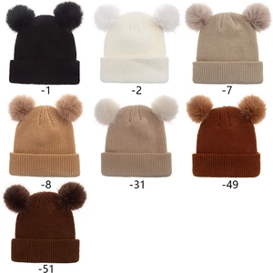 Vue détaillée de sept variantes de couleurs de bonnets en tricot à double pompon pour bébé