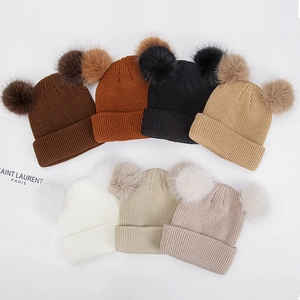 Détail des bonnets tricotés pour bébé avec deux pompons en fourrure en sept couleurs