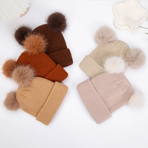 Vue à plat de plusieurs bonnets en tricot à doubles pompons en divers coloris automnaux