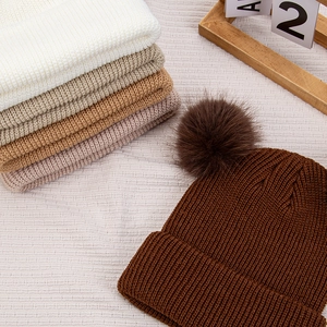 Détails à plat de bonnets en tricot pour bébé avec pompons en plusieurs couleurs terre