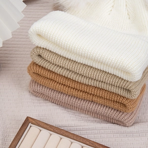 Gros plan de bonnets en tricot pour bébé avec pompons en fourrure sur fond rustique