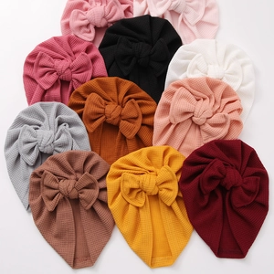 Détail de bonnets turban gaufrés pour bébé avec grands nœuds en plusieurs couleurs vives