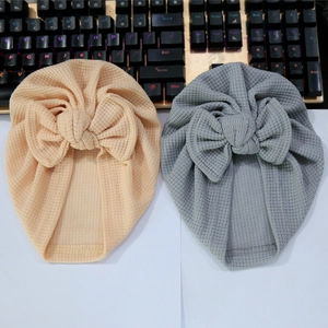 Détail de bonnets turban bébé en tricot gaufré beige et gris avec grands nœuds décoratifs