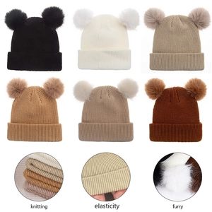 Détails de la maille et des grands pompons en fausse fourrure sur un bonnet bébé hiver