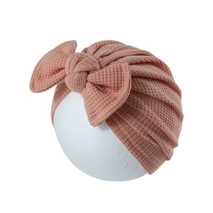 Détail du bonnet turban rose pour bébé en maille gaufrée avec un grand nœud décoratif élégant