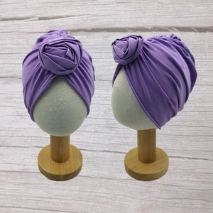 Detailed view of purple baby turban hats with textured 3D rose knot on wooden stands