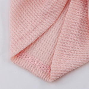 Gros plan sur le tissu gaufré rose montrant la texture et les coutures surjeteuses