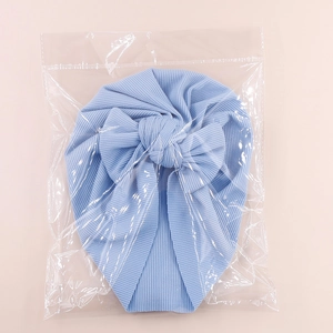 Detail shot of a light blue ribbed baby turban with a knotted bow in plastic packaging