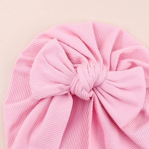 Close-up of pink ribbed baby turban hat featuring a large soft decorative bow