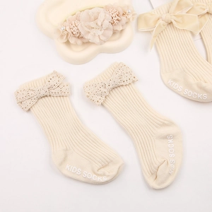 Detailed view of cream baby socks with lace bows and a floral pearl headband set
