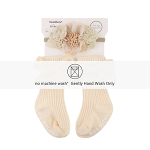 Detail of infant headband with fabric flowers and matching ribbed socks in cream white