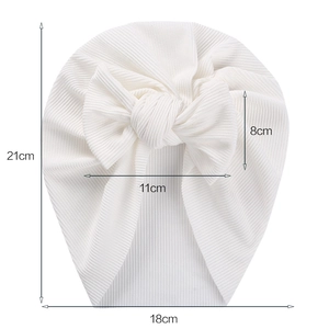 White ribbed cotton baby turban hat with a large bow showing size measurements