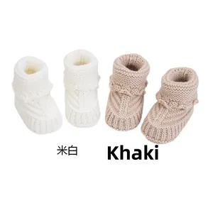 Detail view of off-white and khaki hand-knitted baby socks with soft wool texture