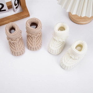 Macro shot of knitted cotton baby boots with textured stripes and wavy fold collars