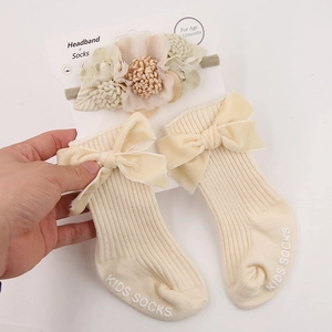 Detail of baby headband and ribbed socks set with floral decor and velvet bows