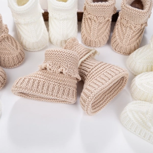 Detailed knit texture of newborn baby booties in warm beige and khaki tones