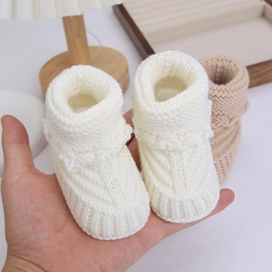 Close-up of hand-knitted warm cotton baby booties with soft wavy texture for newborns