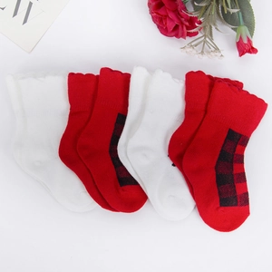 Nahaufnahme von Strick-Weihnachtssocken für Babys mit rotem Karomuster und Rüschen