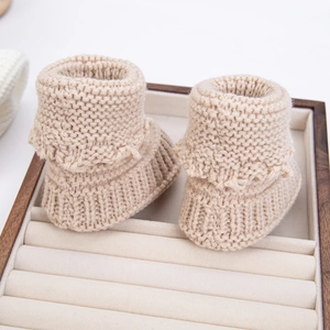 Detailed view of oatmeal knitted baby socks featuring ruffled cuffs and textured weave