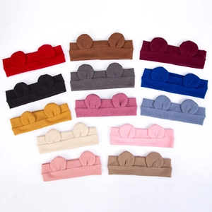 Flat lay of thirteen colorful elastic knit baby headbands with cute animal ear designs