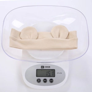 Lightweight baby headband with bear ears weighing 15.1g on a digital scale