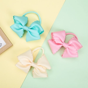 Detail of embroidered grosgrain ribbon bows on elastic nylon headbands for babies
