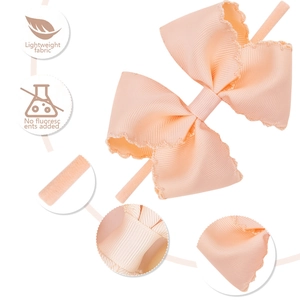 Detail of light peach baby bow headband with scalloped lace edge and elastic fabric band