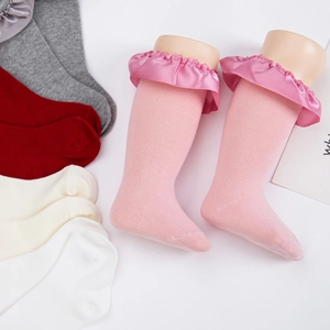 Détail de chaussettes bébé en coton rose avec bordure en dentelle satinée froncée