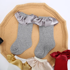 Vue détaillée des chaussettes grises en tricot pour bébé avec volants en satin chic