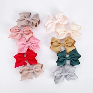 Close-up detail of ten colorful grosgrain ribbon hair bows with delicate scalloped edges