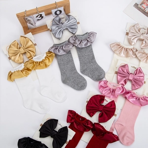 Detail view of baby socks and headband sets with satin ruffles and large bow accents