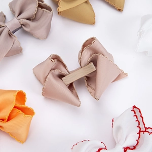 Close-up of handmade ribbed ribbon bow hair clips with scalloped edges and colorful stitching