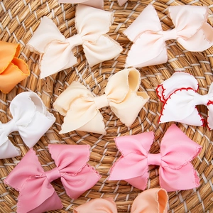 Detail of colorful ribbed ribbon bow clips with contrast stitching on woven background