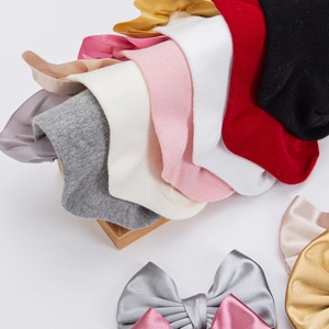 Close-up of baby girl socks with satin bow details in multiple colors on wood blocks