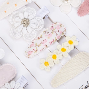 Detailed macro view of embroidered floral hair clips with lace and daisy patterns