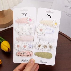 Detail of floral hair clip set featuring embroidered daisies and lace fabric on cards