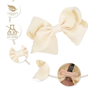 Detail view of cream grosgrain bow clip with scalloped edges and lightweight fabric