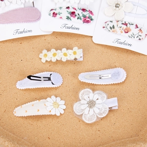 Close-up of floral hair clip set featuring daisy embroidery and lace fabric textures