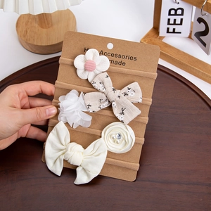 Detail showing five beige floral chiffon baby headbands on a kraft display card