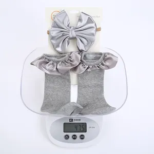 Detailed view of grey baby sock and satin bow headband set weighing about 47.5 grams