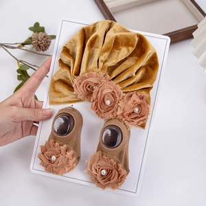 Dettaglio del turbante in velluto e calzini per neonati con fiori e perle decorative