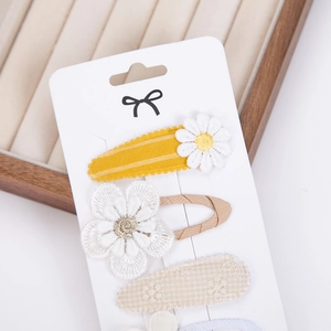 Close-up of floral hair clips with daisy embroidery and fabric textures on display card