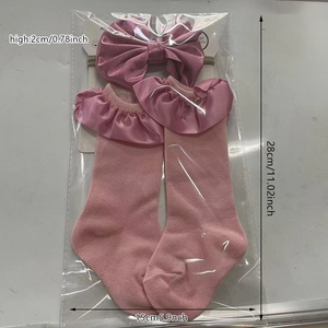 Detailed view of pink infant lace socks and satin bow headband set in transparent packaging